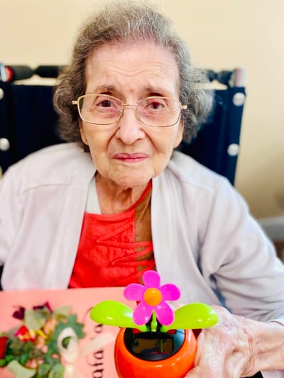 An elderly woman holding a decorated flower pot