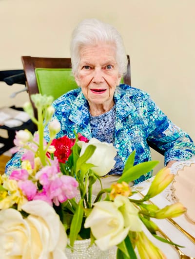 A resident posing with flowers at a dining table