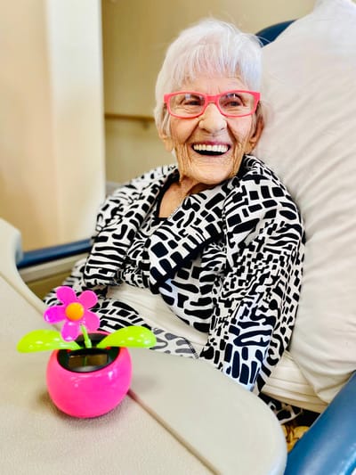 A resident smiling with a flower decoration