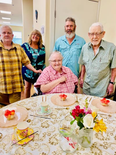 Residents and staff celebrating around a decorated dining table