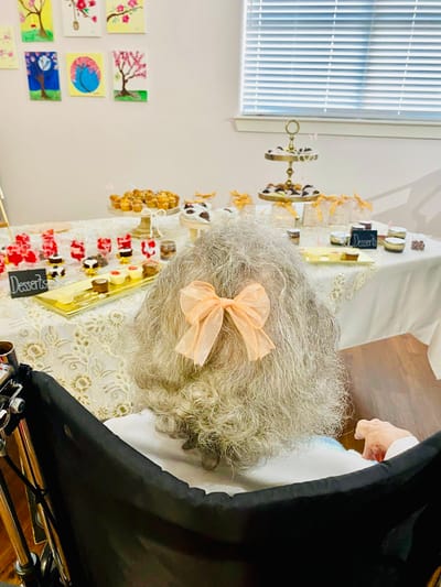 An elderly woman with a bow watching a dessert display