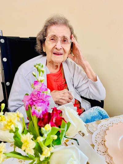 A resident in a wheelchair enjoying company with flowers nearby