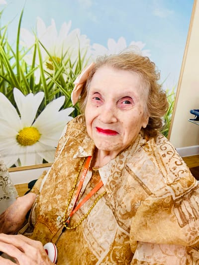 A smiling resident with a flower in her hair
