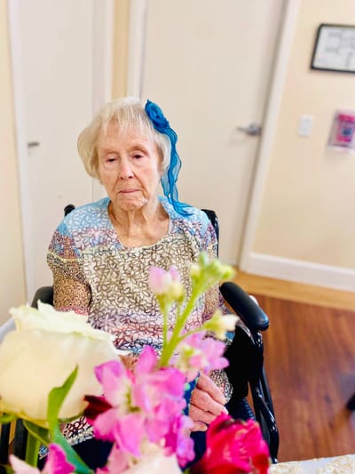 Elderly woman sitting in a wheelchair with flowers in foreground