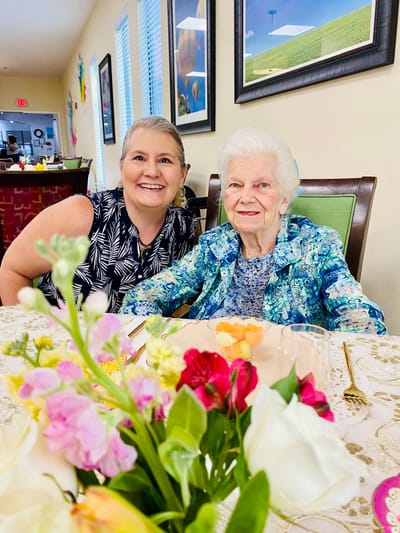 Resident and staff member smiling together at a table