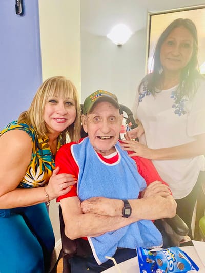 Residents and staff smiling together in an activity room