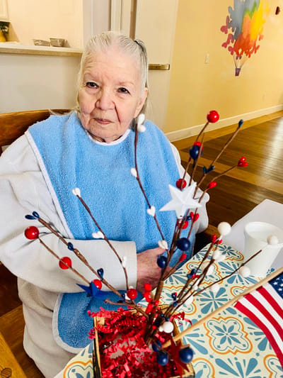 An elderly woman sitting at a decorated table for a holiday.