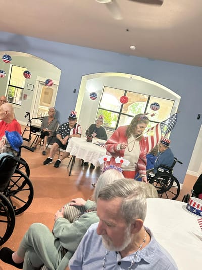 Residents celebrating with decorations and hats in an activity room