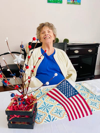 Resident smiling at a festive table with an American flag