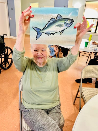 Resident proudly displaying her painting of a fish