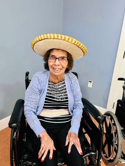 Resident smiling in a sombrero in an activity room