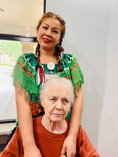 Care staff assisting a resident in a festive outfit