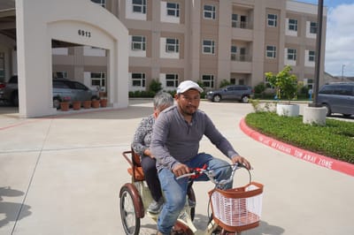 A resident enjoying a tricycle ride outside the facility