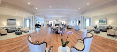Bright common area with seating and piano in a senior living facility