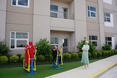 Residents exercising outdoors on fitness equipment