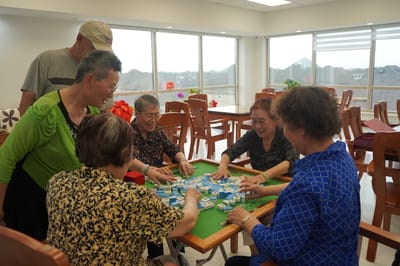 Residents playing mahjong in an activity room