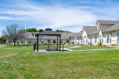 Outdoor gazebo surrounded by grass and buildings