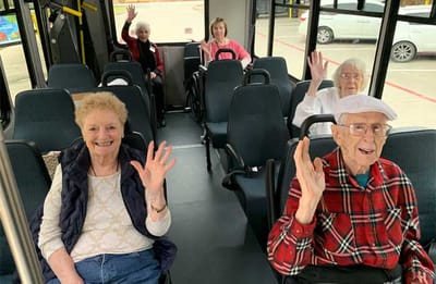 Residents waving from a facility shuttle bus