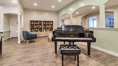 Common area with a grand piano and bookshelves