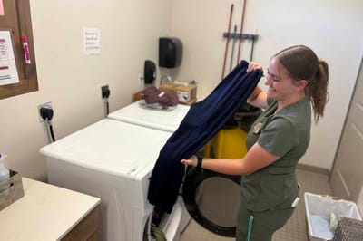 Staff member folding laundry in the facility's laundry room