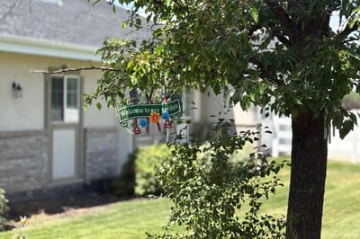 Welcome sign hanging in a garden near the facility