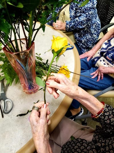 Resident arranging a yellow rose in a vase