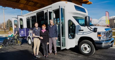 Residents and staff by a facility transport van