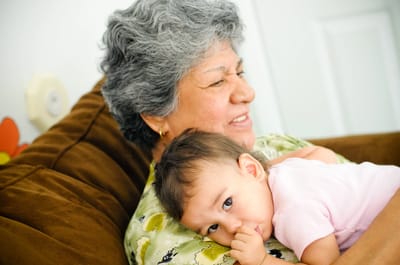 A senior woman cuddling a baby on a couch