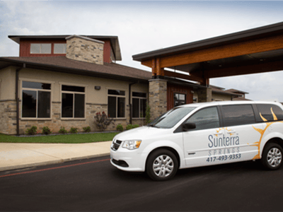 Exterior view of a senior living facility with transport van