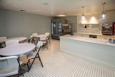 Interior view of a dining room with tables and kitchen area
