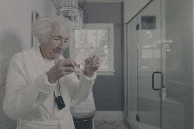 An elderly woman adjusting her glasses in a bathroom
