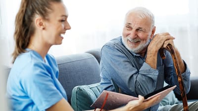 Rocky Mountain Care – Summit Ridge Assisted Living OC LLC, nursing home in Douglas, WY — Caregiver interacting with smiling senior man in sitting area