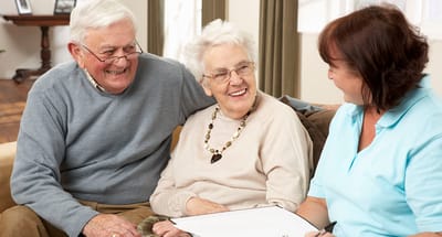 Two senior residents enjoying conversation with staff member