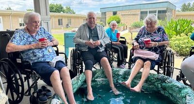 Residents enjoying time outdoors, with their feet in a pool