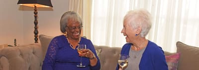 Two residents enjoying drinks in a cozy lounge
