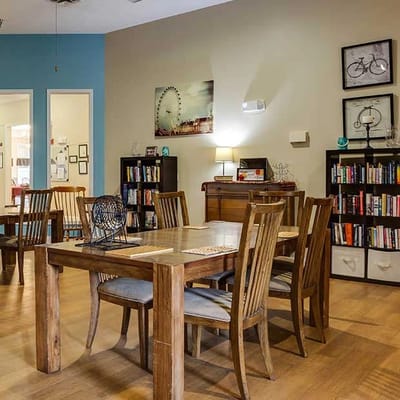 Bright common area with wooden dining tables and bookshelves