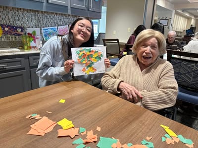 Resident enjoying a craft activity with staff assistance