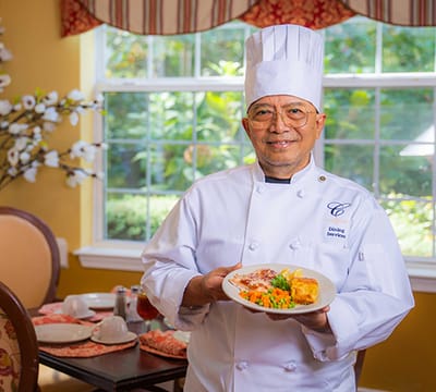 Chef presenting a meal in a bright dining area