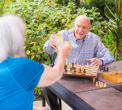 Two seniors enjoying a game of chess outdoors