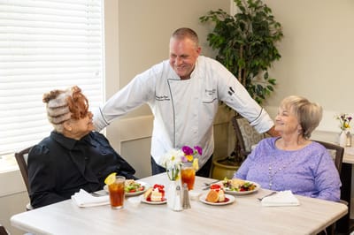 Residents enjoying a meal with a staff member in the dining area