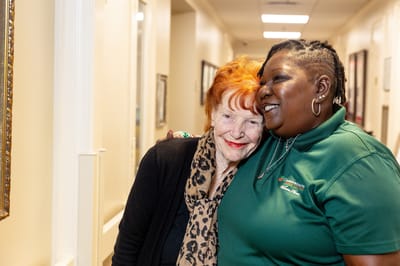 Staff member embracing a resident in a facility corridor