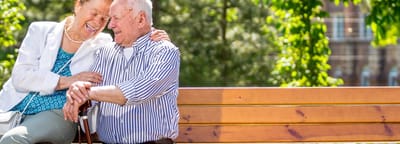 A happy elderly couple sitting on a bench in a park