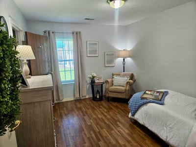 Bright interior of a resident room with a bed and chair