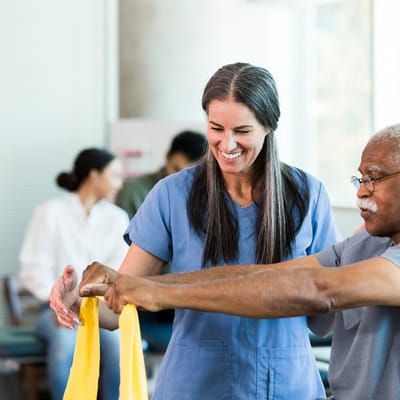 A staff member assisting a resident with therapy exercises
