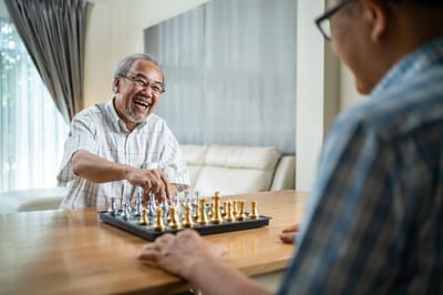 Two seniors playing chess in a bright, inviting room