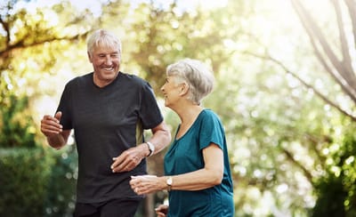 Senior couple walking together in a green outdoor space