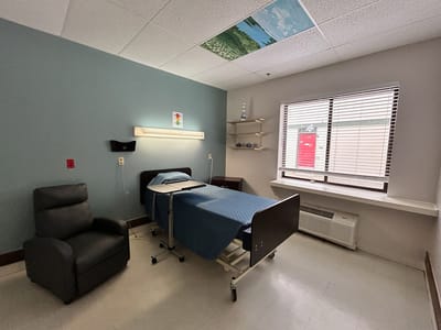 A private resident room featuring a bed and chair
