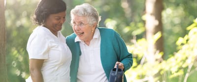 Staff assisting a senior in a sunny outdoor space