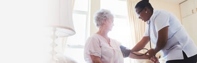A caregiver taking a resident's blood pressure indoors