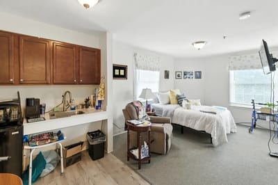 A well-furnished private resident room with a bed and sitting area